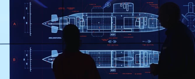 Two silhouettes standing against a blueprint of a submarine on a screen