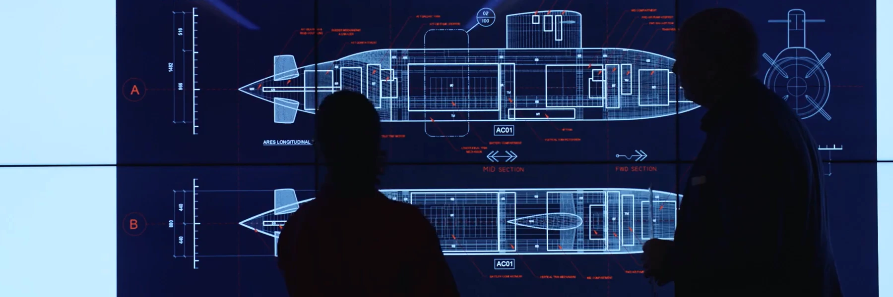ARES-Submarine Two silhouettes standing against a blueprint of a submarine on a screen