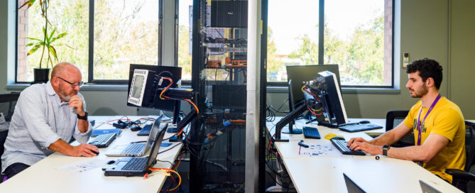 Two men working on computers facing each other