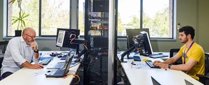 A side on image of two men on computers at their work stations